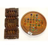 A wooden solitaire game with marbles and a carved wooden extending book rack.