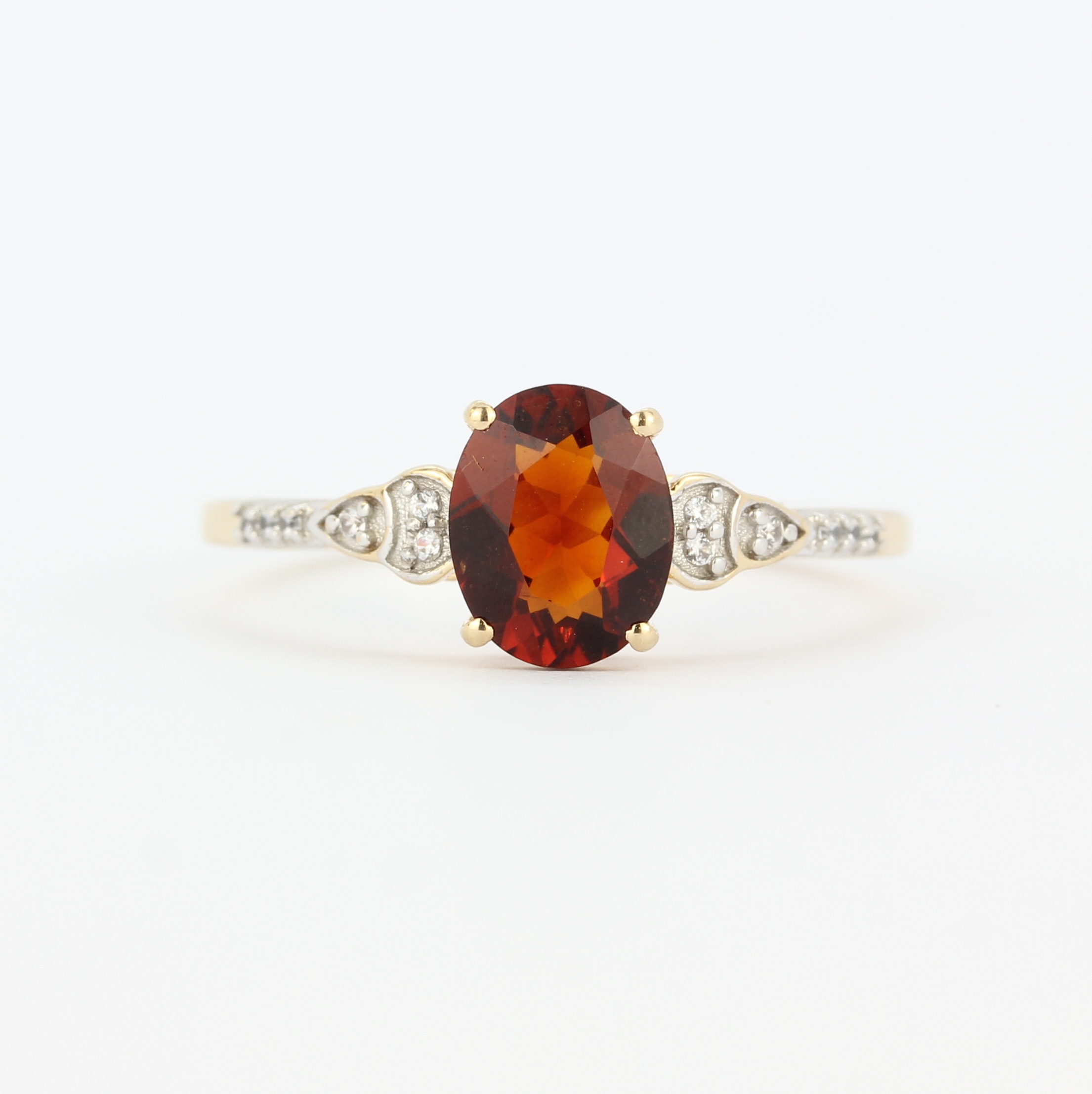 A 9ct yellow gold ring set with an oval cut hessonite garnet and diamond set shoulders, (U).