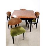 A 1960's stained teak extending dining table and four chairs with painted legs and green upholstery.