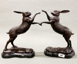 A pair of bronze figures of boxing hares on grey marble bases.