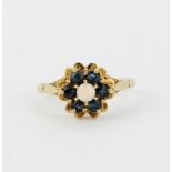 A hallmarked 9ct yellow gold flower shaped ring set with a round cabochon opal surrounded by round