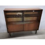 A teak sliding door bookcase/ display cabinet, 122 x 102 x 28cm.