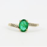 A hallmarked 9ct yellow gold solitaire ring set with an oval cut emerald and diamond set