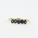 A hallmarked 9ct yellow gold ring set with pear cut sapphires, (U).