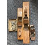 Three wooden antique woodworking planes and a metal plane guide.