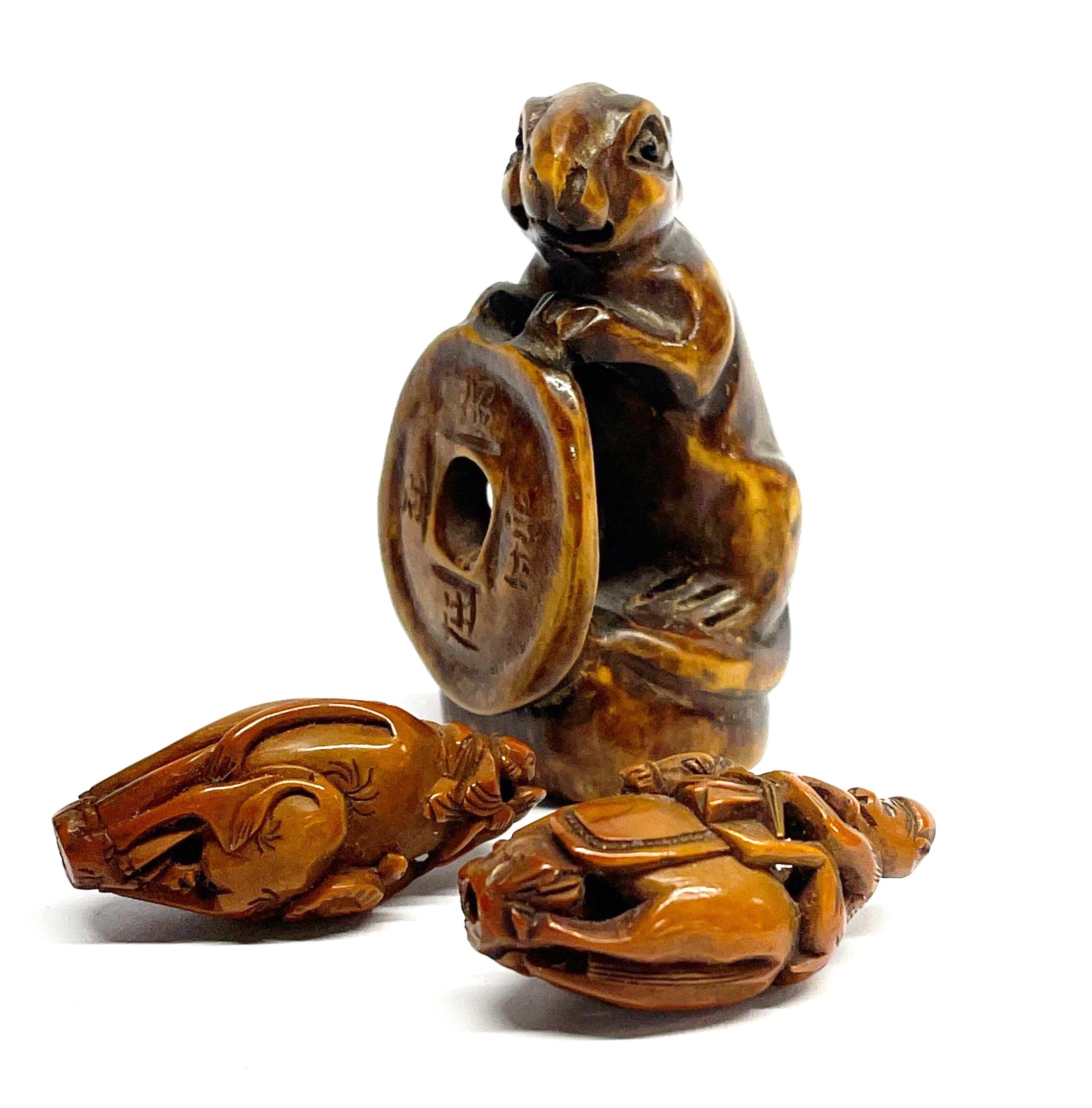 A Japanese carved walnut netsuke with polished ebony eyes, H. 6cm, together with two finely carved