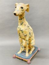 A large painted plaster figure of a dog sitting on a cushion, H. 54cm, slightly A/F to back tassle.