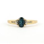 A 9ct yellow gold ring set with an oval cut London blue topaz and diamonds, (T.5).