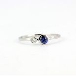 An 18ct white gold ring (stamped 750) set with a brilliant cut diamond and a sapphire, (N).