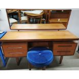 A 1970's teak four drawer, mirror backed dressing table with a teak and blue upholstered stool,