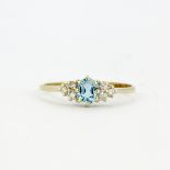 A hallmarked 9ct yellow gold ring set with an oval cut aquamarine and diamonds, (O.5).