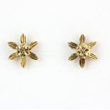 A pair of 9ct yellow gold flower shaped earrings set with a brilliant cut diamond, L. 1cm.