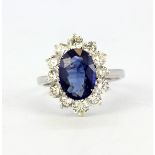 An 18ct white gold (stamped 750) cluster ring set with an oval cut sapphire and diamond set