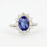 An 18ct white gold (stamped 750) cluster ring set with an oval cut tanzanite surrounded by brilliant