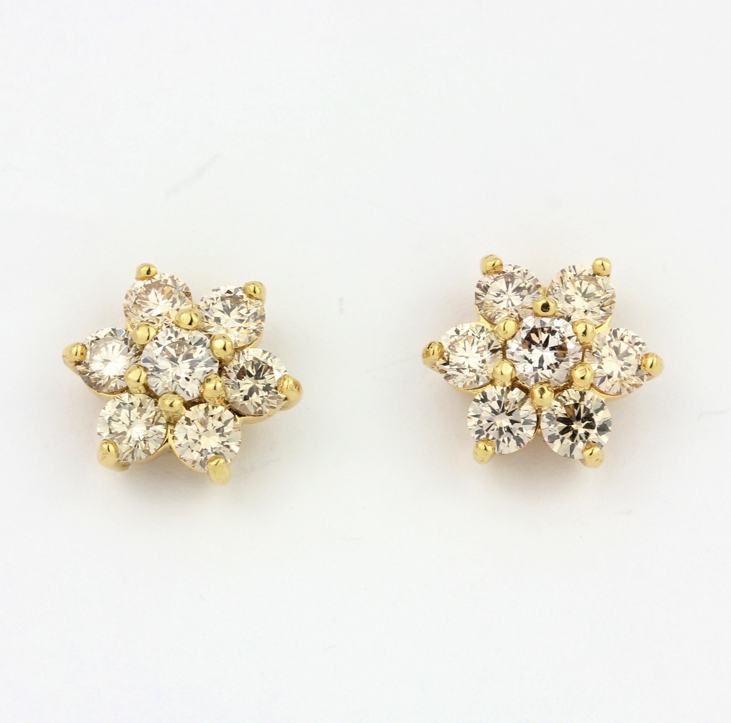 A pair of yellow metal (tested 18ct gold) daisy cluster earrings set with brilliant cut diamonds,