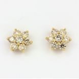 A pair of yellow metal (tested 18ct gold) daisy cluster earrings set with brilliant cut diamonds,