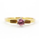 An 18ct yellow and white gold ring set with a round cut pink topaz, (N).