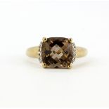 A 9ct yellow gold ring set with a checker board cut smokey quartz and diamond set shoulders, (P.5).