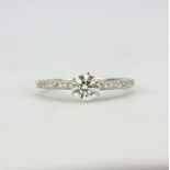 An 18ct white gold (stamped 750) solitaire ring set with a brilliant cut diamond and diamond set