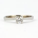 A white metal (tested high carat gold) solitaire ring set with a brilliant cut diamond, approx. 0.