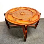 A carved folding legged coffee table from Haiti with carved decoration on both sides of tribal