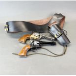 Two good quality colt replica revolvers with leather belt and holster.