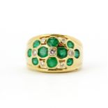 An 18ct yellow gold (stamped 750) ring set with oval cut emeralds and diamonds, (R).