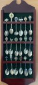 Collection of 18 White metal, Enamel Vintage Collectable spoons on wooden rack, with green felt