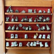 Collection of 47 China or Metal Thimbles on wooden shelf with red felt backing. 17 white China