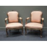 A pair of Louis XV style carved walnut fauteuil armchairs with fleur de lys upholstery