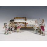 A group of continental porcelain figurines to include a sheep sheerer; together with, Sampson putti;