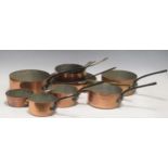 A set of five copper saucepans with cast iron handles, another similar set with brass handles and