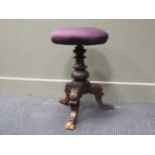 A late Victorian carved piano stool with adjustable revolving top on hipped cabriole legs and