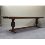 A long oak refectory table, the rectangular top with carved cup and cover supports united by a