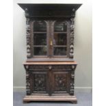 A 19th century Flemish oak cabinet, the upper section with a pair of oval glazed doors extensively