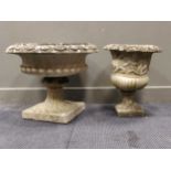 Two composite garden urns, one with a gadrooned body, the other decorated with scrolling floral