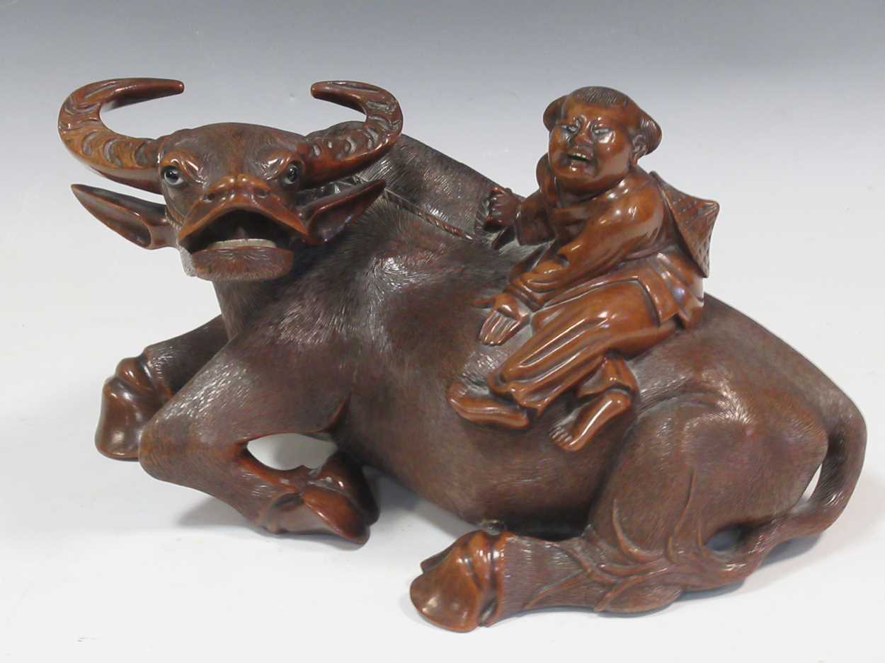 An Asian carved hardwood water buffalo with rider, circa 1900