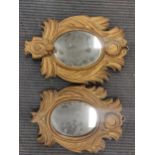 A pair of carved gilt wood wall mirrors, the oval plates within leaf carved frames 35 x 23cm (one