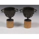 A pair of late 19th century bronze vessels with yellow marble bases, together with a black leather