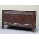 An 18th century pegged oak three panel coffer, the rising lid over carved muntins on stile feet,