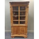 A 19th century pine floor standing corner cupboard, the upper section with pair of glazed doors