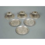 Three early 20th century Iranian metalwares silver dwarf candlesticks together with three coasters,