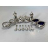 Two silver three piece condiment sets with spoons and liners and a pair of silver rimmed glass salts