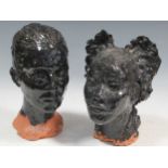 A pair of black glazed clay sculptures busts of girls heads, thought to possibly be by George