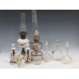 Three oil lamps, glassware including decanters, jugs, pair figural porcelain candlesticks, etc