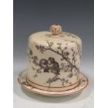 An Almonds & Sons ceramic cheese cover and stand decorated with birds on a branch, overall height