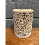 An ivory brush pot with intricate carved details depicting a village scene of boats, vendors selling