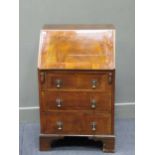 A George III style walnut veneered small bureau, with feather banded fall front and bronze wrythen
