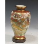 A modern Japanese satsuma vase, decorated with fanciful birds and ducks on a lake, on a wooden
