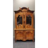 A late 19th century French provincial carved pine display cabinet with crescent moulded corice on